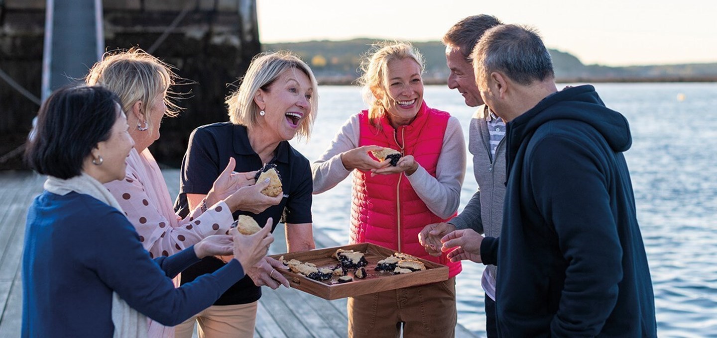 Travelers sampling fresh oysters on a dock.